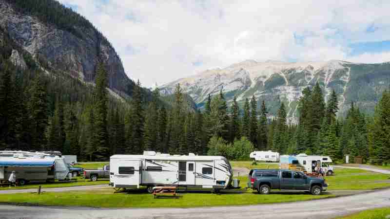 A beautiful campsite featuring RVs amidst lush forests and towering mountains for a peaceful getaway., tags: caravan - pexel