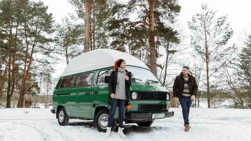 A couple enjoys a winter adventure with their green campervan in a snowy forest., tags: road - pexel